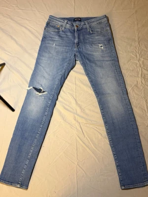 Jack & Jones jeans ljusblå – Slim fit – 31/32 – Mycket bra skick (snygga slitningar) - Säljer ett par ljusblå Jack & Jones jeans, slim fit, storlek 31/32, i mycket bra skick. Har snygga slitningar som ger en modern och trendig look.  Perfekta för streetwear, laidback eller Y2K-inspirerade outfits. Funkar riktigt bra med sneakers och hoodie eller enkel t-shirt.  Mått: Midja: 36 cm Längd: 101 cm  • Märke: Jack & Jones • Passform: Slim fit • Skick: Mycket bra  Jack & Jones 2