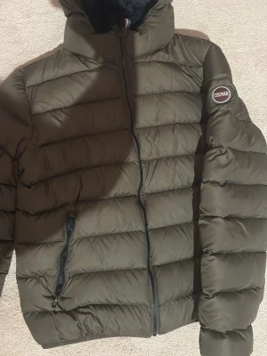 Mörkgrön pufferjacka från Colmar - Säljer en mörkgrön pufferjacka från Colmar med luva och dragkedja framtill. Jackan har två sidofickor med dragkedja och en snygg Colmar-logga på ärmen. Perfekt för kalla dagar och riktigt skön att bära.