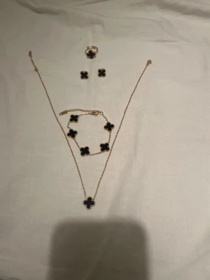 Fyrklöver svart set - Bilderna visar ett smycken set av fyrklöver 18k guldpläterade med svarta stenar. Set av halsband, armband örhängen och ring. 