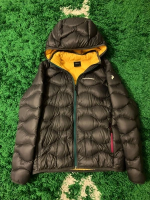 Peak Performance Multi color Dunjacka - Säljer en svart dunjacka från Peak Performance med gul insida och huva. Jackan har quiltad design, dragkedja framtill och två fickor med dragkedja. Perfekt för kalla dagar och riktigt snygg detalj med den kontrasterande gula insidan. Inga fläckar eller hål förekommer men den är flitigt använd.