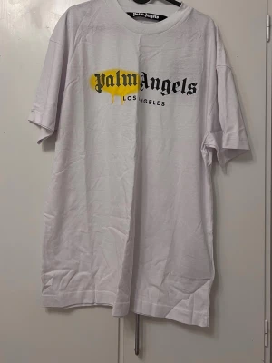  vit t-shirt XL - Säljer en vit t-shirt  i storlek XL passar L oxå T-shirten har ett stort tryck framtill med svart text och en gul spray-effekt över loggan. Klassisk rund hals och korta ärmar. Tillverkad i mjuk bomull för skön känsla.