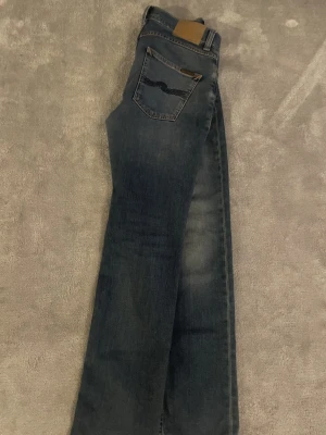 Blå jeans från Nudie Jeans - Säljer ett par ljusblå  blå jeans från Nudie Jeans  i modellen grim Tim.