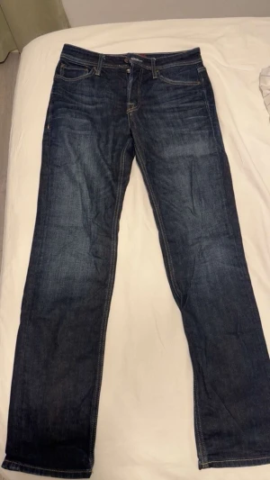 Mörkblå jeans från Jack & Jones - Säljer ett par mörkblå jeans från Jack & Jones med klassisk femficksdesign och kontrastsömmar. Jeansen har rak passform och normal midja. Materialet är slitstarkt jeans-tyg i bomull. Perfekta till en avslappnad stil. Ordniariepris 899