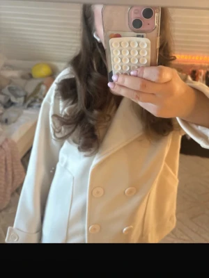 Vit kappa från Design by Si - Säljer en stilren offwhite kappa från Design by Si. Verkligen superfin, men kände att färgen inte riktigt passade mig och hade hellre velat ha en svart😇 HELT NY MED PRISLAPP