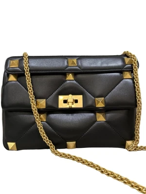 Svart Valentino Garavani väska - Säljer min svarta  Valentino väska i mjukt skinn med quiltad design och stora guldfärgade nitar. Perfekt för dig som vill ha en rymlig statementväska med lyxig känsla. Bra skick!