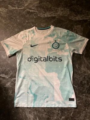 Nike Inter Milan matchtröja  - Säljer en unik Inter Milan matchtröja från Nike med världskarta-mönster i ljusblått och vitt. Tröjan har tryckta sponsorer, klubbmärke och nummer 14 på ryggen. Tillverkad i lätt polyester som andas, perfekt för fotboll eller samling.