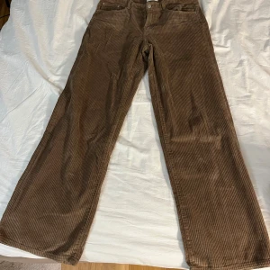 Bruna manchesterbyxor med vida ben - Säljer ett par bruna manchesterbyxor med breda räfflor och vida ben, normal passform. Perfekta för dig som gillar retrostil och vill ha något bekvämt och snyggt till vardags. Knappt använda, mycket bra skick