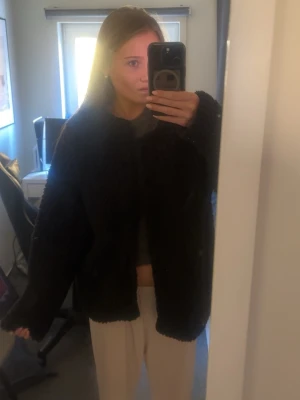 Svart teddyjacka från Creamie - Mysig svart teddyjacka från Chiquelle med oversized passform och lång ärm. Jackan har en fluffig och mjuk. Enkel att matcha med olika outfits.