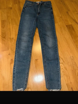 Blå skinny jeans Stradivarius - Säljer ett par klassiska blå skinny jeans från Stradivarius i storlek 36. Jeansen har hög midja, fem fickor och stängs med knapp och dragkedja. Materialet är stretchigt jeans och benen är smala hela vägen ner.