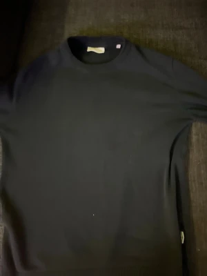 Svart tröja från Lindbergh Relaxed Fit - En stilren svart tröja från Lindbergh i relaxed fit. Tröjan har rund halsringning och långa ärmar, perfekt för dig som gillar en enkel och clean look. Passar till allt och är superenkel att matcha med andra plagg.