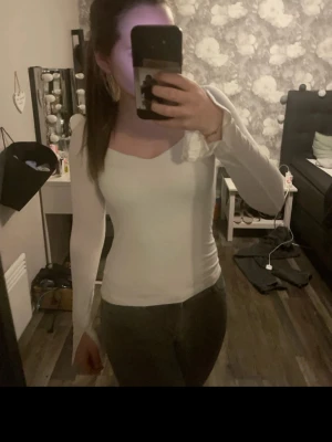 Vit långärmad topp med slits  - Säljer en vit långärmad topp med slits . Toppen har en snygg, något fyrkantig ringning och är gjord i ett stretchigt material som sitter skönt mot kroppen. Perfekt att styla med jeans eller kjol.