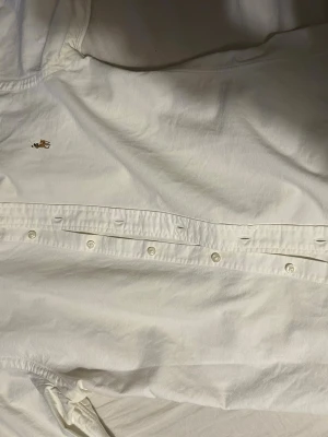 Vit skjorta från Polo Ralph Lauren - Klassisk vit skjorta från Polo Ralph Lauren med broderad logga på bröstet. Skjortan har knappar framtill och på kragen, samt lång ärm. Tillverkad i mjuk bomull för en clean och tidlös look. Otroligt stilren skjorta! Kom pm för mer info om så önskas.