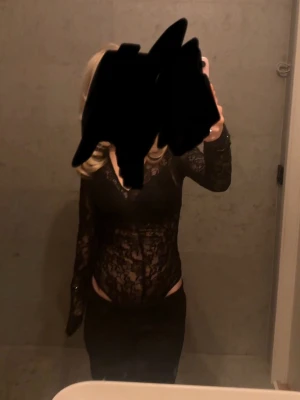 Svart spetsblus med v-ringning - Säljer en svart långärmad blus i genombruten spets med v-ringad hals. Toppen är figurnära och har transparenta partier som ger en snygg och trendig look. Perfekt att styla med höga byxor eller kjol.