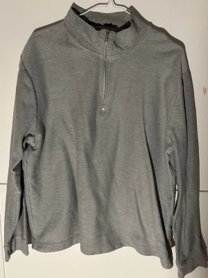 Grå half zip tröja från Topman - Säljer en stilren grå långärmad tröja från Topman i storlek XL. Tröjan har en hög krage och praktisk half zip-dragkedja framtill. Perfekt för lager-på-lager och chill dagar. Materialet är mjukt och känns skönt mot huden.
