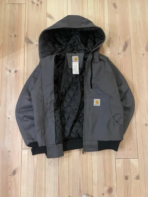 Carhartt Duck Active Jacket - Säljer nu den eftertraktade Carhartt Duck Active Jacket. ❗️ Gray & Black 🎨  Medium / M , sitter möjligtvis något mindre 📏 | Skick: 9.5/10, väldigt fint ✅  Mycket bekväm och varm men ändå riktigt fet 😮‍💨 