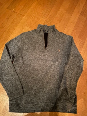 Grå half zip tröja från Polo Ralph Lauren - Snygg grå långärmad tröja från Polo Ralph Lauren med half zip. Tröjan har ett litet broderat Polo-logo på bröstet. Storlek M, skriv om ni har någon fråga!