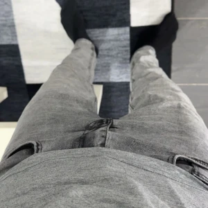 Grå jeans från Black Denim - Säljer ett par grå slim fit jeans från Black Denim. Jeansen har klassisk femficksdesign, smal passform och är tillverkade i stretchig denim för extra komfort. Perfekta för dig som gillar en tajt look och vill ha ett par stilrena jeans i garderoben.