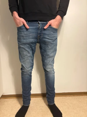 Blå jeans från tiger of sweden - Säljer ett par blå tiger of sweden jeans med slim passform och klassisk femficksdesign. Jeansen har en snygg tvätt med lätt slitning och smal siluett som sitter tajt längs benen. Perfekt för dig som gillar en modern och stilren look.