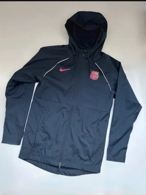 Blå Nike FC Barcelona vindjacka - Mörkblå Fc Barcelona Vindjacka. Är fortfarande i bra skick. Ny pris ca 1200kr