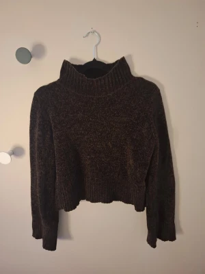 Brun polotröja från Gina Tricot - Mysig brun polotröja från Gina Tricot i chenille-liknande material. Tröjan är croppad med bred ribbad kant nedtill och vid ärmslut. Hög polokrage och långärmad modell som passar perfekt till höst och vinter. 💕
