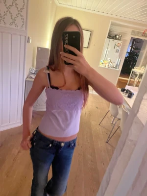 Ljuslila spetsdetaljerad linnetopp - Supersöt ljuslila linnetopp med tunna axelband och spetsdetaljer över bysten. Toppen är croppad och har en feminin look med mjukt tyg och stretchig passform. Perfekt att styla med jeans eller kjol för en chill vibe. Vintage!! 