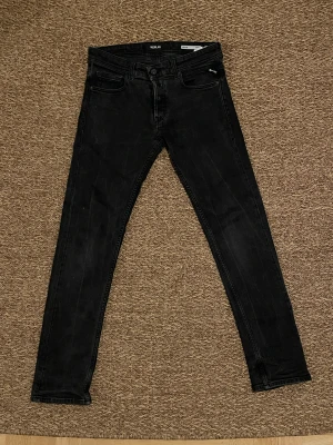  Svarta Replay Grover jeans - Svarta Replay jeans i grover modell med klassisk femficksdesign och diskreta detaljer. Jeansen har smal passform hela vägen ner och är tillverkade i stretchigt jeansmaterial för extra komfort. Perfekta för dig som gillar en tajt siluett.
