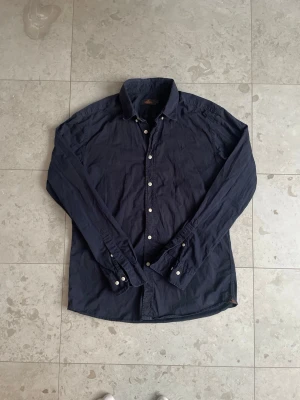 Morris skjorta marinblå  - Säljer nu denna snygga marinblåa skjortan från Morris, eftersom att den har blivit för liten för mig. Har använts relativt mycket, men fortfarande i fint skick! Storlek: L men passar M. | Hör mer än gärna av dig vid fler frågor eller prisförslag!