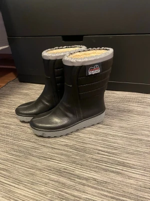 Svarta vinterstövlar med grå kant - Svarta vinterstövlar från Original med grå kant upptill och mjukt, ljust foder. Yttermaterialet är slitstarkt och fodret är i polyester. Sulan är grå och har ett grovt mönster för extra grepp. Perfekt för kalla dagar och snö.