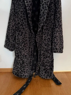 Morgonrock från DKNY S - Säljer en leopardmönstrad  mörkgrå/svart morgonrock från DKNY. Knytband i midjan, två fickor fram. Storlek S. Bra skick.
