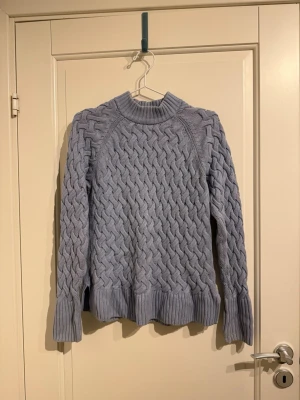 Blå kabelstickad tröja - Skön tröja i bomull med kabelstickning och lite längre ärmar.