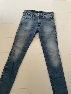 Replay Anbass blå skinny jeans - Snygga Replay Anbass jeans i blå tvätt med skinny passform. Klassisk femficksdesign, dragkedja och knapp framtill. Jeansen har coola slitningar och detaljerade bakfickor med broderi. Perfekta för dig som gillar en smal siluett och stilren look.30W 32L