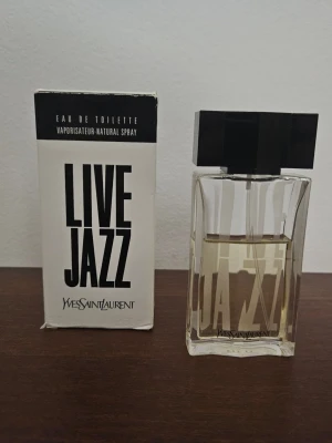 Yves Saint Laurent Live Jazz Eau de Toilette 50ml - Live Jazz från Yves Saint Laurent är en Eau de Toilette med en volym på 50 ml. Slutad tillverkad sen många år sen och är sällsynt. Köptes ny i förpackning från Ebay i april 2024 av en italiensk säljare. Ca 35/50 ml kvar. Denna batch är troligen från sent 90 tal när den lanserades.