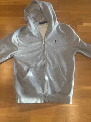 Grå hoodie från Ralph Lauren. L - Väldigt stilig tröja med lite slitage. Tyvär har snöret vid luvan försvunnit. Skriv om fler bilder och priset kan diskuteras 
