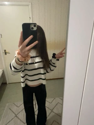 Vit och svart randig stickad tröja - Säljer en vit stickad tröja med svarta horisontella ränder. Tröjan har en loose passform, ribbade muddar och är långärmad. Perfekt för dig som gillar en chill och stilren look. Passar till både jeans och mjukisbyxor.