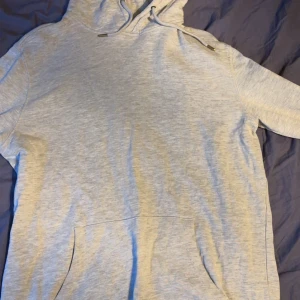 Ljusgrå hoodie från On Our Terms - Säljer en stilren ljusgrå hoodie från On Our Terms i storlek M. Tröjan har huva med snörning och en stor magficka framtill. Perfekt för dig som gillar en enkel och clean look. Materialet är mjukt och skönt, troligtvis bomull eller bomullsblandning.