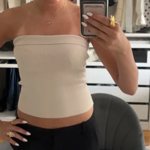 Beige bandeau tubtopp - Säljer en stilren beige bandeau tubtopp med tight passform. Toppen är ärmlös och har en enkel, clean look som passar perfekt till både jeans och kjol. Materialet är stretchigt och bekvämt, vilket gör den lätt att bära hela dagen . Stl s från bikbok. Aldrig använd men utan prislapp