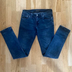 Blå skinny jeans från Nudie Jeans - Säljer ett par mörkblå skinny jeans från Nudie Jeans i modellen Tight Long John. Klassisk femficksdesign, snygga slitningar och orange sömmar. Jeansen är i stretchigt bomullsmaterial och har en smal passform som sitter fint hela vägen ner.  Aldrig använda skick 9/10 Nu pris 1300kr mitt pris 400kr🤩