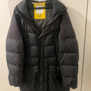 Svart dunjacka från G-Star RAW XXL - Säljer en svart dunjacka från G-Star RAW i storlek XXL. Jackan är lång, har huva, dragkedja och knappar framtill samt flera fickor. Fylld med äkta dun för extra värme och har en clean, sportig look med diskret logga på ärmen.