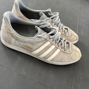 Beige Adidas Gazelle sneakers - Hej! Säljer mina adidas gazelle i storlek 44 2/3. De är i färgen grå och ljusblå men är lite smått smutsiga(går att rengöra). Inga defekter som påverkar passformen. Ingen skolåda ingår
