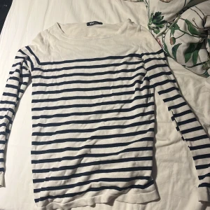 Randig långärmad tröja Gina Tricot XS - Säljer en vit och marinblå randig långärmad tröja från Gina Tricot i storlek XS. Tröjan har klassisk båtringad hals och är stickad i mjukt material. Perfekt för en chill och stilren look. Längst ner på tröjan finns de en liten slits på vardera sida som du kan se på fjärde bilden. Tröjan är i bra skick men har använts ganska många gånger! 
