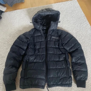 Svart Peak Performance dunjacka - Säljer min svarta peak performance dunjacka i storlek 160. Den är i modellen tomic hood. Jackan är använd en säsong och är i väldigt fint skick. Finns en liten skada på underarmen (se bild) men det är ingen man lägger märke till. Priset går att förhandla!💕