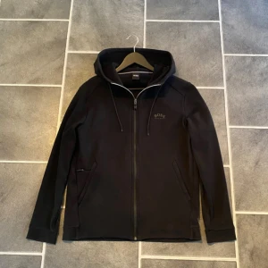 Svart Boss kofta - Säljer denna stilrena Boss koftan i väldigt bra skick på grund av för liten storlek, inga tecken på användning och har den feta loggan enligt mig istället för den simpla ”boss” . Nypris 1800