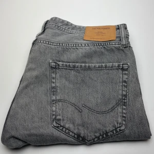 Grå jeans från Jack & Jones - Snygga grå jeans från Jack & Jones i klassisk femficksmodell. Jeansen har en cool tvättad look och är tillverkade i slitstarkt bomullsmaterial. Perfekta för dig som gillar en avslappnad och stilren vibe.