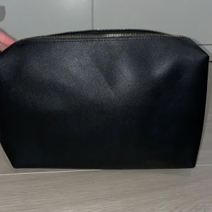 Svart kuvertväska i skinn - Stor svart nessesär ca 30cm x 15. Går bra att ha i vanliga väskor också