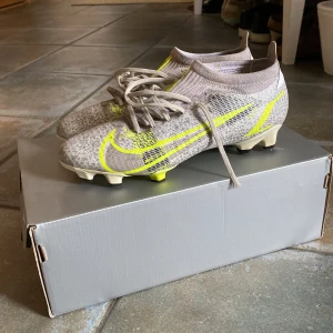 Nike mercurial elite - Snygga Nike Mercurial fotbollsskor med glittrig silverdesign och gula detaljer. Skorna har en strömlinjeformad passform och snörning för optimal kontroll på planen. Perfekta för den som vill sticka ut med stil. Obs skon tillverkas inte längre!