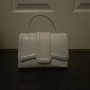 Vit axelväska från Zara  - Säljer en vit axelväska från Zara med croco-mönstrad yta och silverfärgad kedja. Väskan har både handtag och axelrem i kedja. 