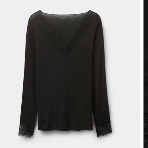 Svart långärmad topp med spets - Svart långärmad topp med v-ringning och snygga spetsdetaljer både vid halsringningen och vid ärmsluten. Toppens enkla design gör den lätt att matcha och spetsen ger en extra touch av stil.