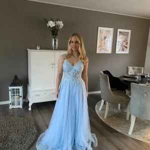 Ljusblå långklänning med spets - Säljer en drömmig ljusblå långklänning med v-ringad överdel och vackra spetsdetaljer. Perfekt för bal eller student! Klänningen från JJ’s House och är endast använd en gång.