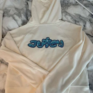 Juicy Couture vit hoodie med blått tryck - Säljer detta super ikoniska settet från juicy couture. Settet säljs inte mer och köptes för 2 år sen. Har knappast används eftersom att den är för stor på mig. Tröjan är i storlek L och byxorna i M. Settet har en pytte liten fläck som man kan se annars är den som i nyskick❤️