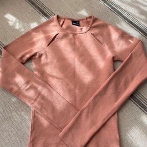 Rosa långärmad topp från Gina Tricot - Säljer en snygg ljusrosa långärmad topp från Gina Tricot i storlek XXS. Toppen har coola slitsdetaljer vid axlarna och är gjord i mjuk bomull. Perfekt för dig som gillar stilrena plagg med en twist. Passar dig som vill ha en slim passform.